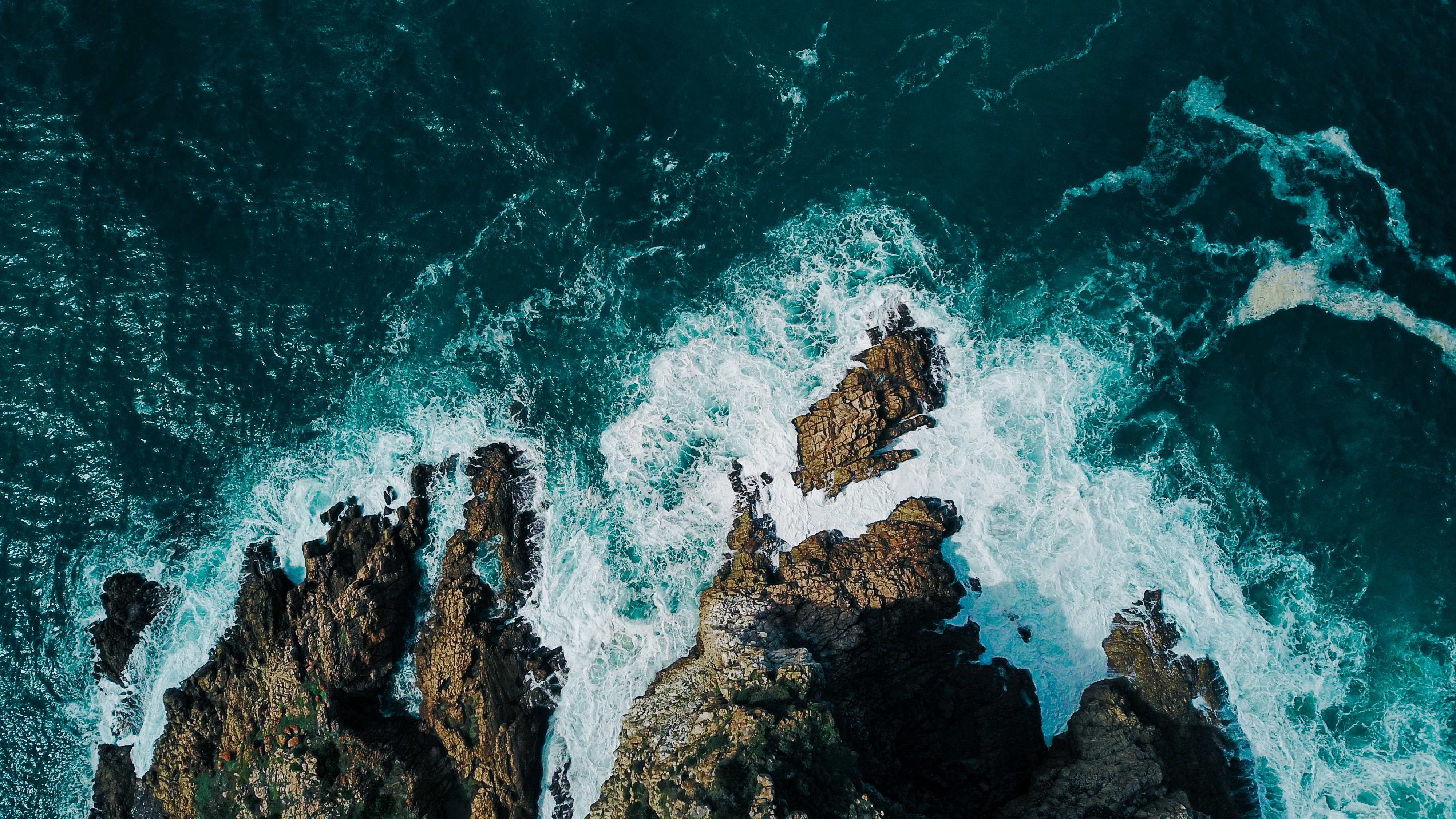 An aerial view of a rocky coastline with ocean waves.
