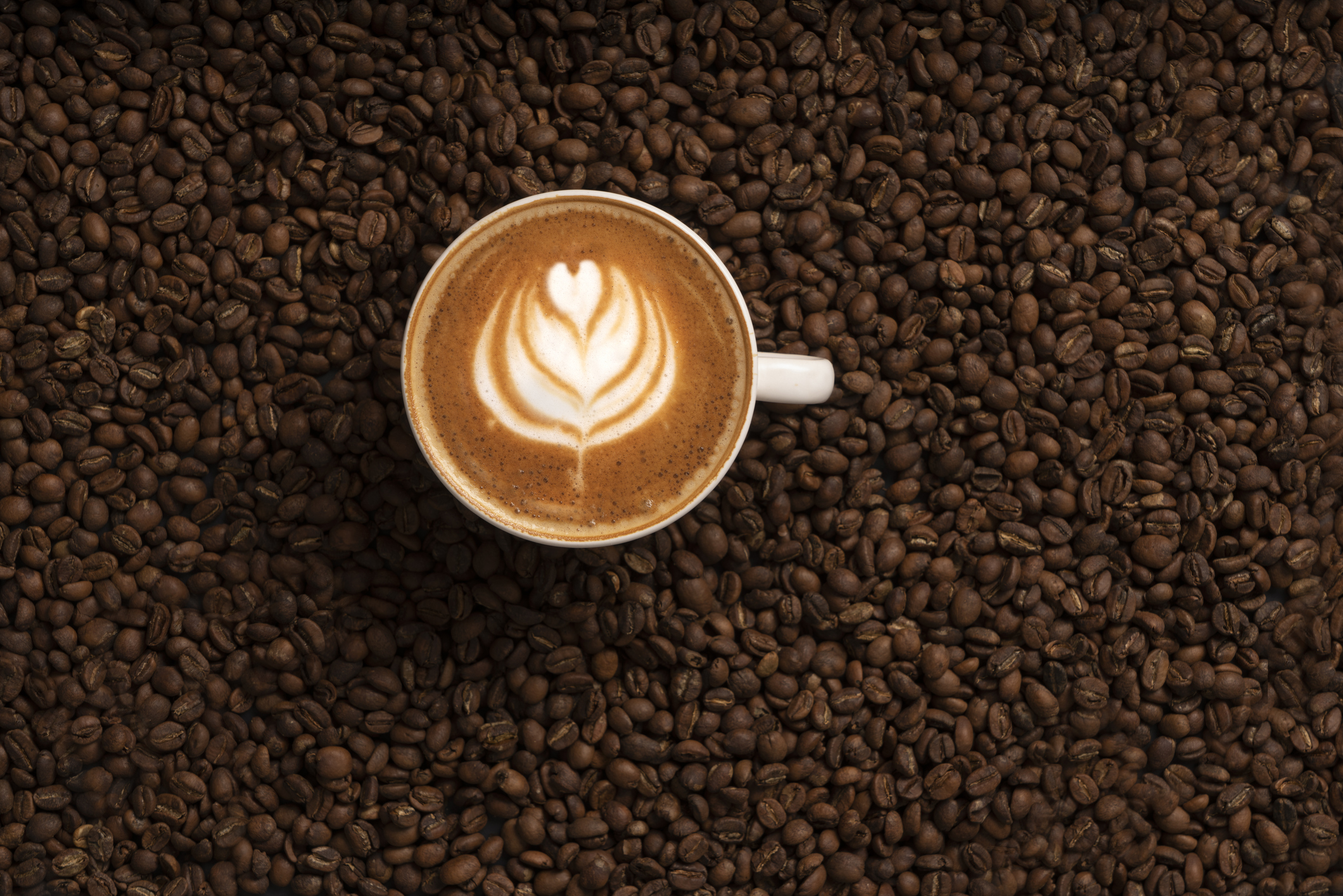 A cup of coffee with art on a coffee beans background